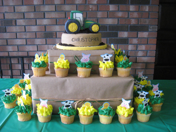 John Deere Tractor Cake on stand with surrounding matching farm cupcakes.