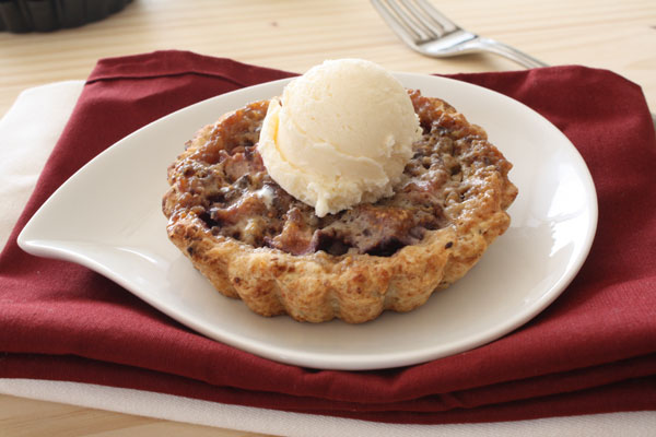 Fresh Fig Tart on white plate over a maroon napkin with fork.