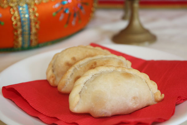 Three fried gujiya on a red napkin 