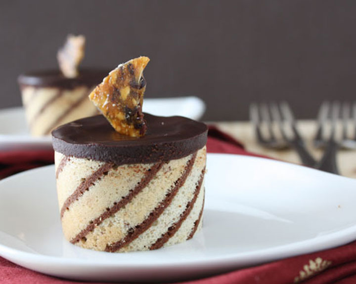 Hazelnut mousse entremet on a white plate and red napkin with forks in the background.