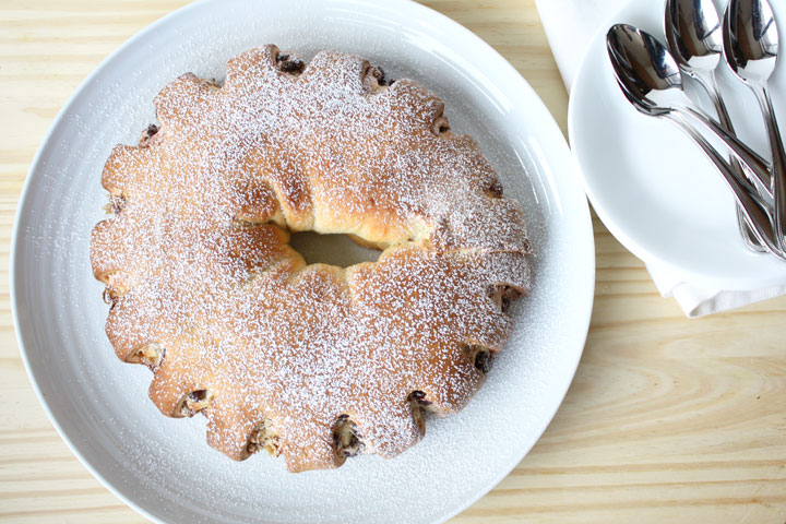 Top view of Meringue Coffee Cake is stuffed with chocolate, cinnamon and walnuts on a white platter with spoons off to the side.