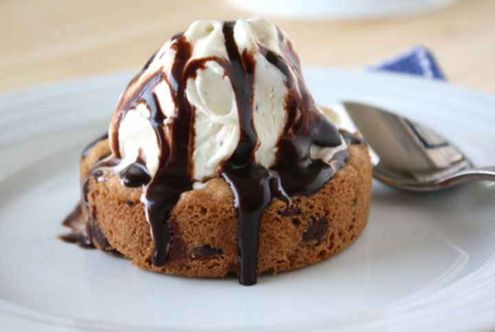 Chocolate chip cookie sundae with vanilla ice cream scoop and chocolate sauce.