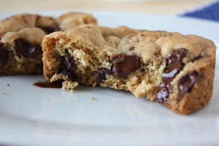 This  chocolate chip cookie broken in half on a white plate.