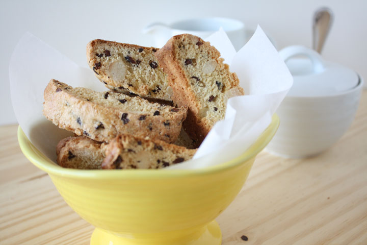 Almond biscotti with cocoa nibs in a yellow bowl.