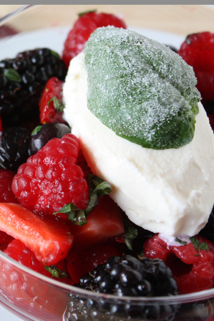 Close up of frosted basil leaf garnishing summer berry salad cocktail.