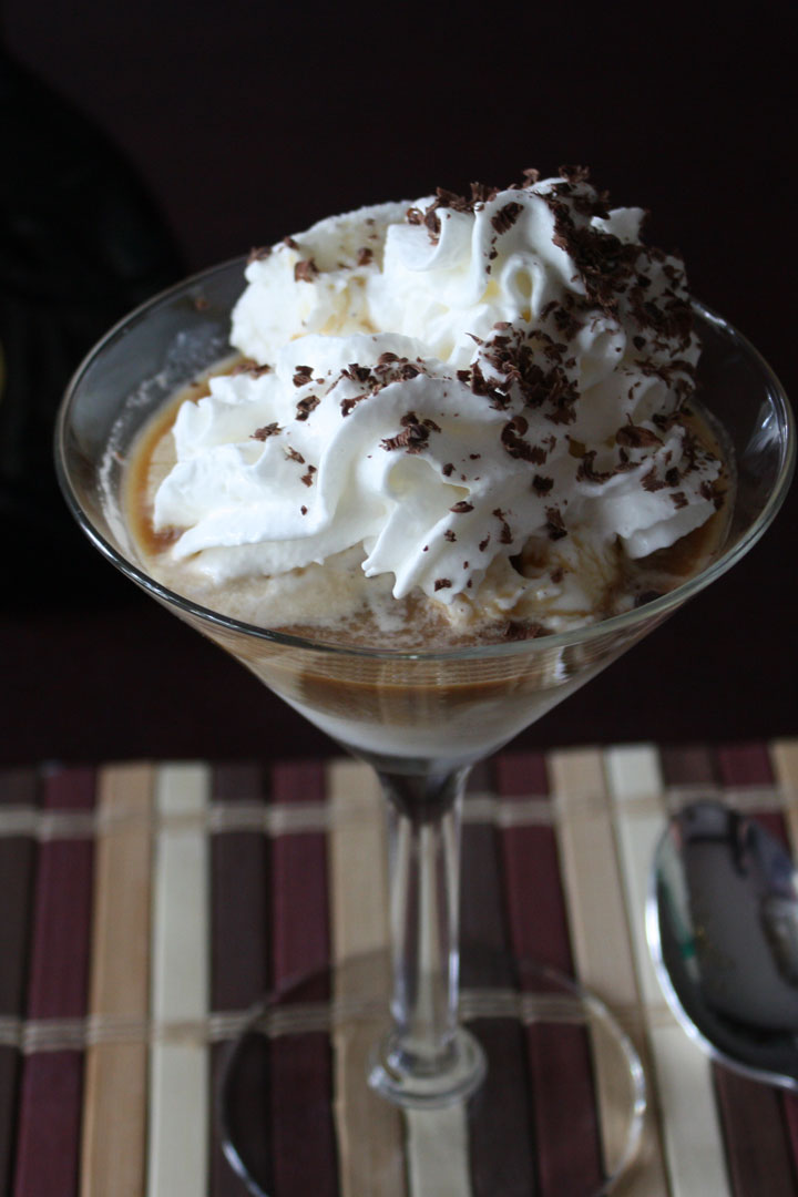 Affogato topped with whipped cream and chocolate shavings in a martini glass.