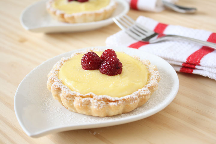 Lemon Tart on a white plate with fork and napkin the background.