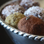 Variety of coated cardamom chocolate truffles in a silver bowl. Pistachio, Cocoa Powder and Coconut coated cardamom truffles.