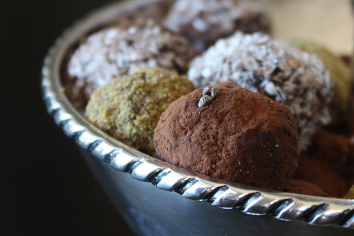 Variety of coated cardamom chocolate truffles in a silver bowl. Pistachio, Cocoa Powder and Coconut coated cardamom truffles. 