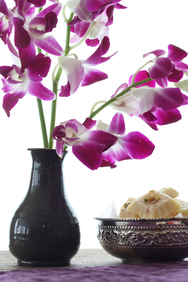 Orchids in a vase next to a bowl of coconut burghs