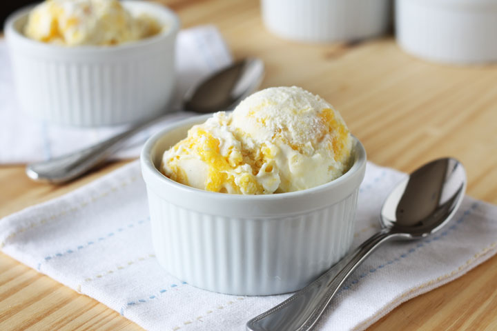 Mango swirl ice cream in a white bowl.