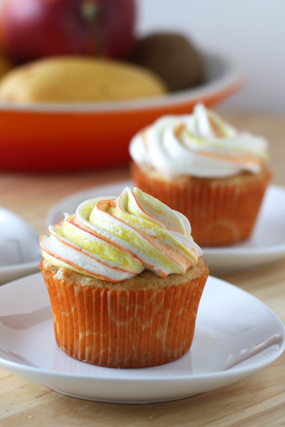 Mango Cupcake with vanilla buttercream swirled on top in a white dish.