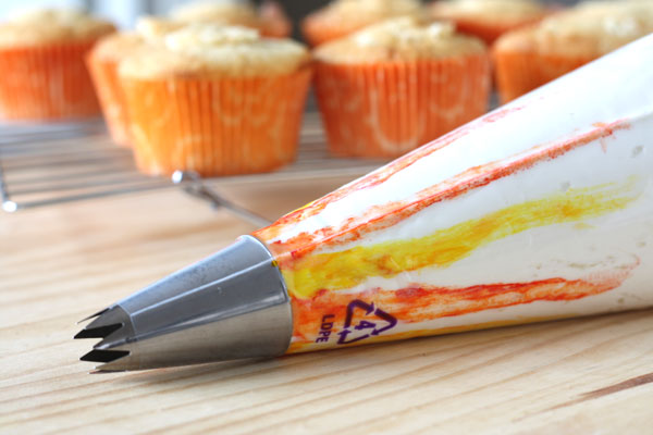 Piping bag filled with mango buttercream showing colors used to create swirl. 