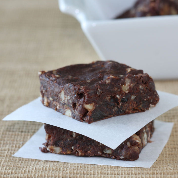 Two vegan brownies stacked between parchment paper.