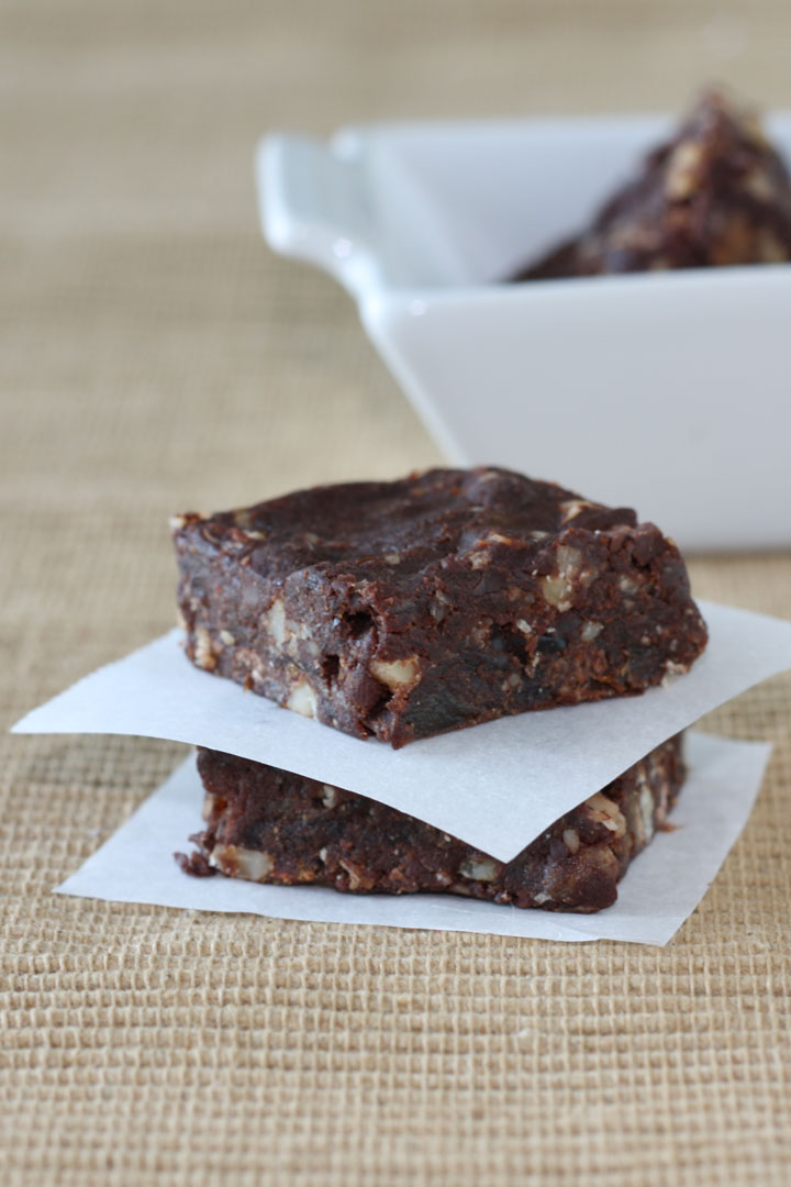 Two vegan brownies stacked between parchment paper.