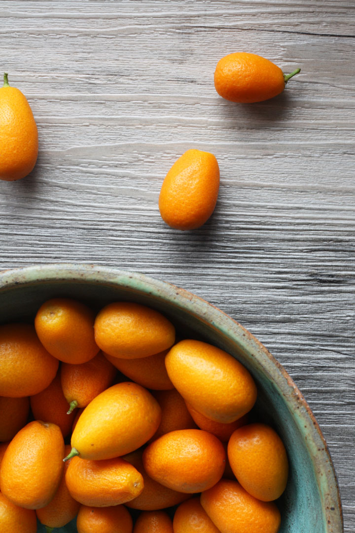 Kumquats in a bowl on wooden surface