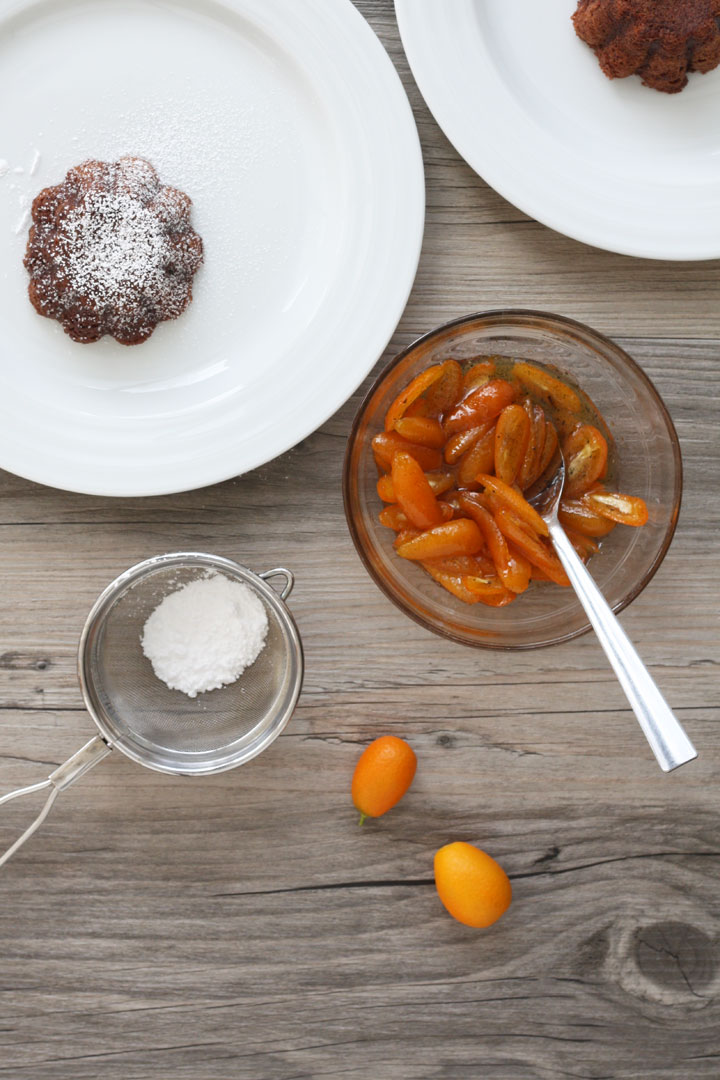 Chocolate lava cake in a plate with bowl of kumquat sauce on the side