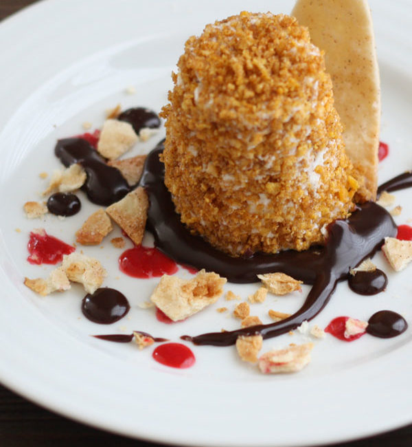 Mexican fried ice cream in a plate with chocolate sauce, raspberry sauce and cinnamon tortilla chips.