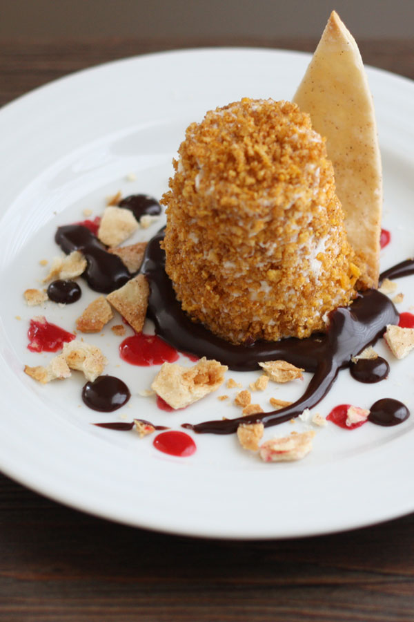 Mexican fried ice cream in a plate with chocolate sauce, raspberry sauce and cinnamon tortilla chips.