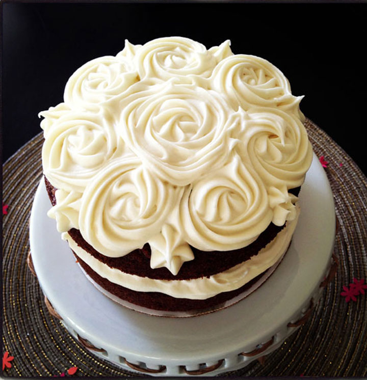 Top view of six inch carrot cake with cream cheese frosting roses on the top.