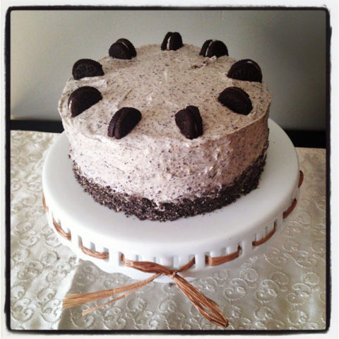 Cookies and Cream Chocolate Cake with mini oreos sitting on a white cake pedestal