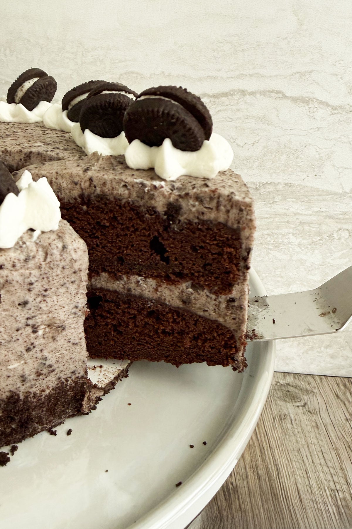 Slice of six inch chocolate Oreo cake  being cut out of the cake and showing two chocolate layers and cookies and cream filling