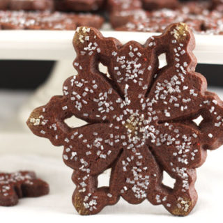 chocolate peppermint snowflake cookie with mor cookies on pedestal in background