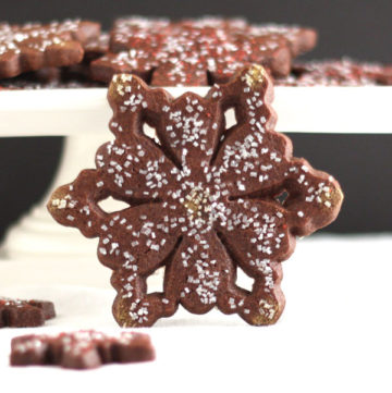 chocolate peppermint snowflake cookie with cookies on pedestal in background