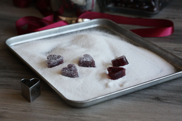 Wine pate de fruit being coated with sugar in a tray.