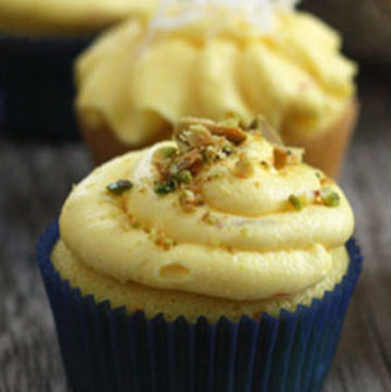 Saffron cupcake with saffron buttercream and pistachio garnish on top.