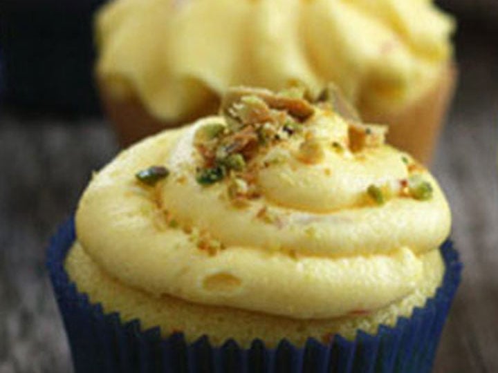 Saffron cupcake with saffron buttercream and pistachio garnish on top.