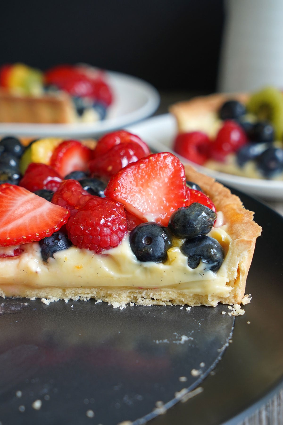 Cut fruit tart showing pastry cream layer under fruits.
