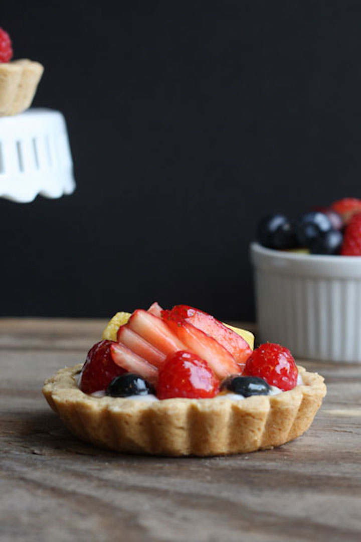 Mini-Fruchttorte mit Erdbeeren, Blaubeeren und Ananas, die mit einer glänzenden Glasur überzogen ist.