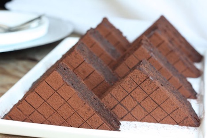 Triangle shaped brownies lined up in a white tray.