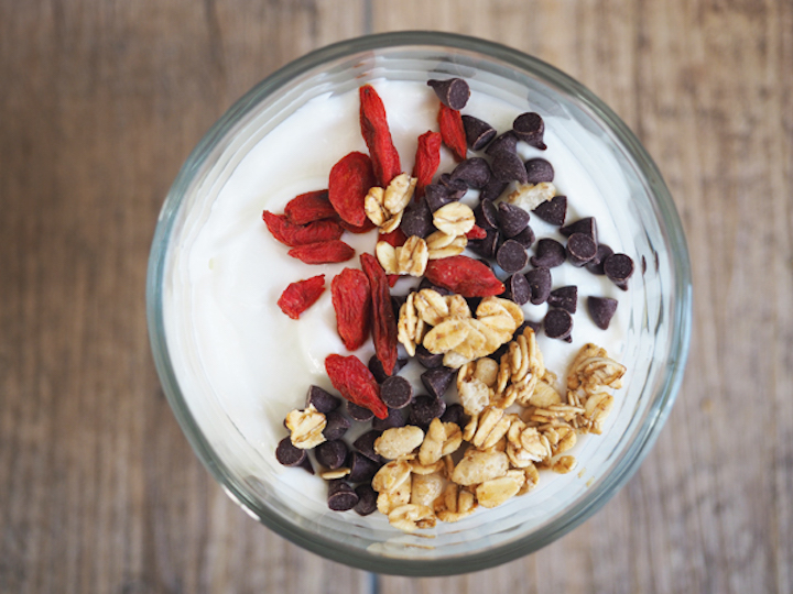 Top view of vanilla yogurt parfait with granola, chocolate chips and goji berries.