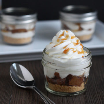 Apple Pie Cheesecake Jars- graham crackers layered with cooked spiced apples and cheesecake and whipped cream. A quick recipe that's as easy as pie!
