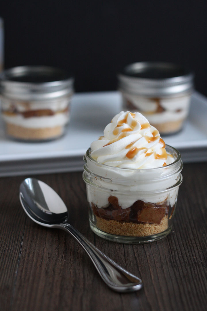 Apple Pie Cheesecake Jars- graham crackers layered with cooked spiced apples and cheesecake and whipped cream. A quick recipe that's as easy as pie!