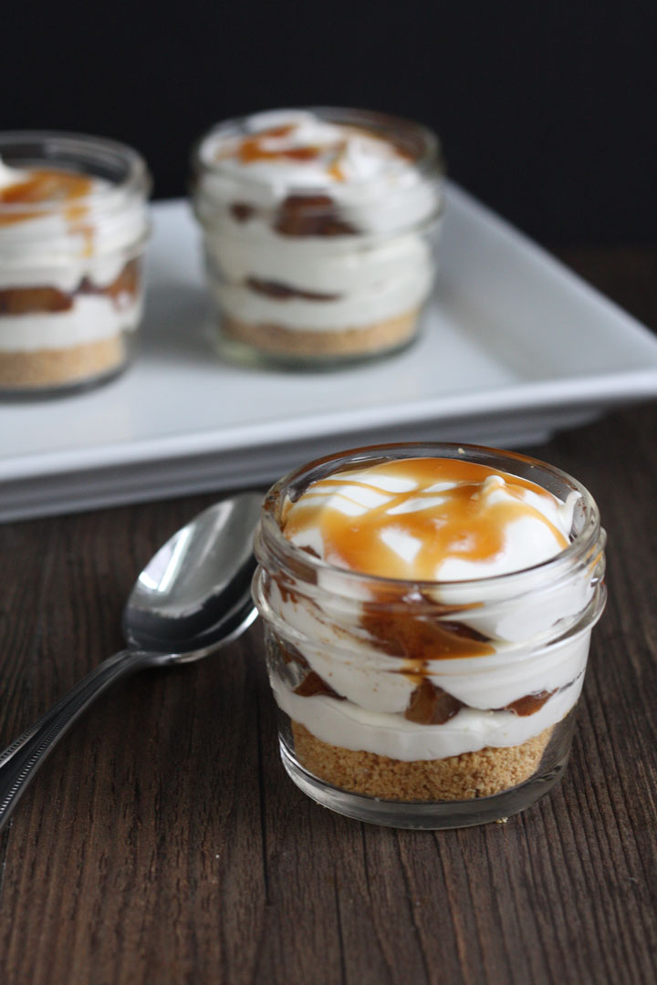 Apple Pie Cheesecake Jars- graham crackers layered with cooked spiced apples and cheesecake and whipped cream. A quick recipe that's as easy as pie!