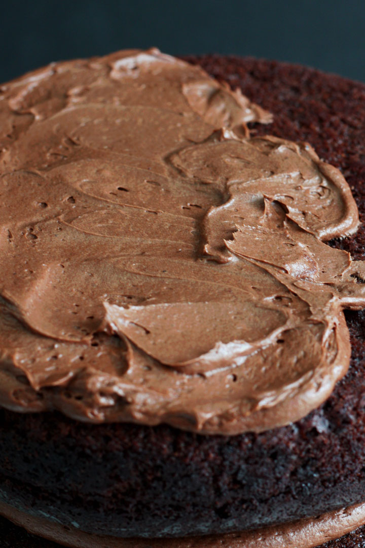 Chocolate cake layer with chocolate fudge frosting spread on top.