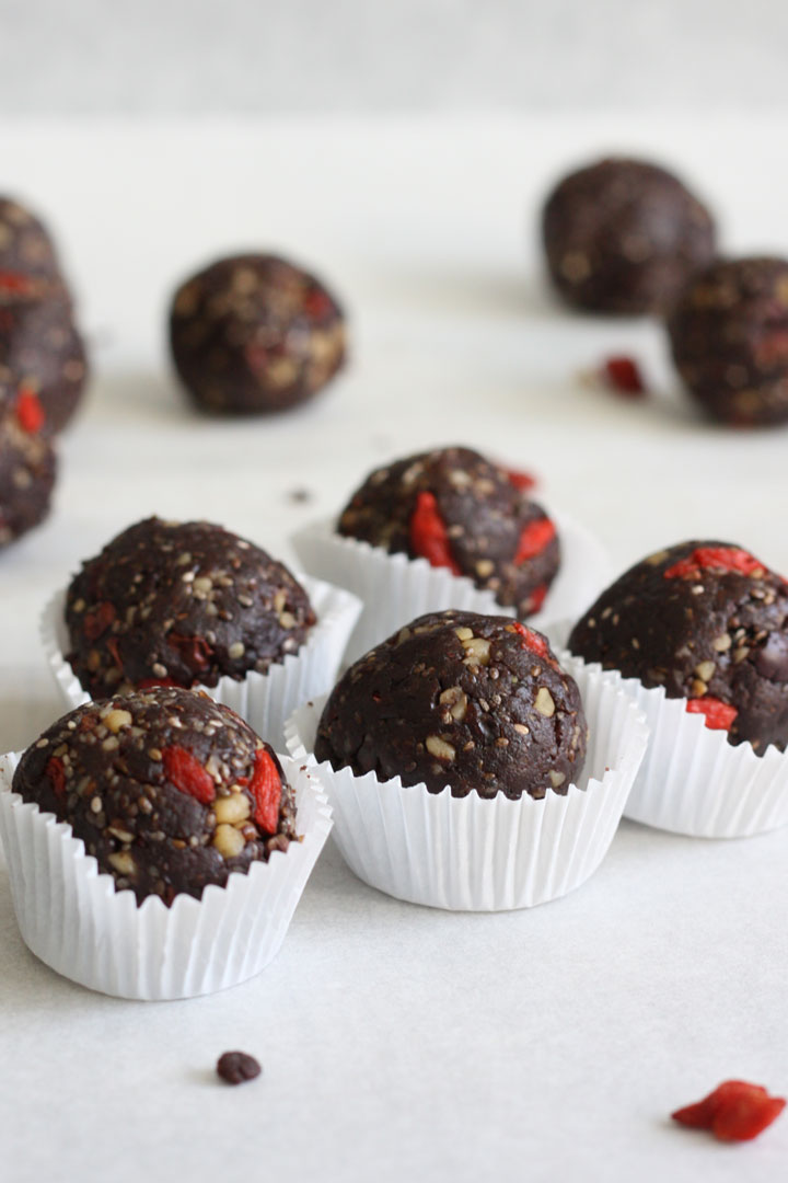 Rolled ball variations of the no bake healthy brownies. Brownie balls are in individual white mini cupcake liners.