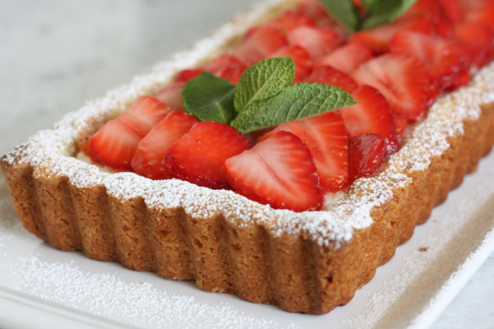 Close up view of one end of the tart filled with mascarpone and topped with strawberries.