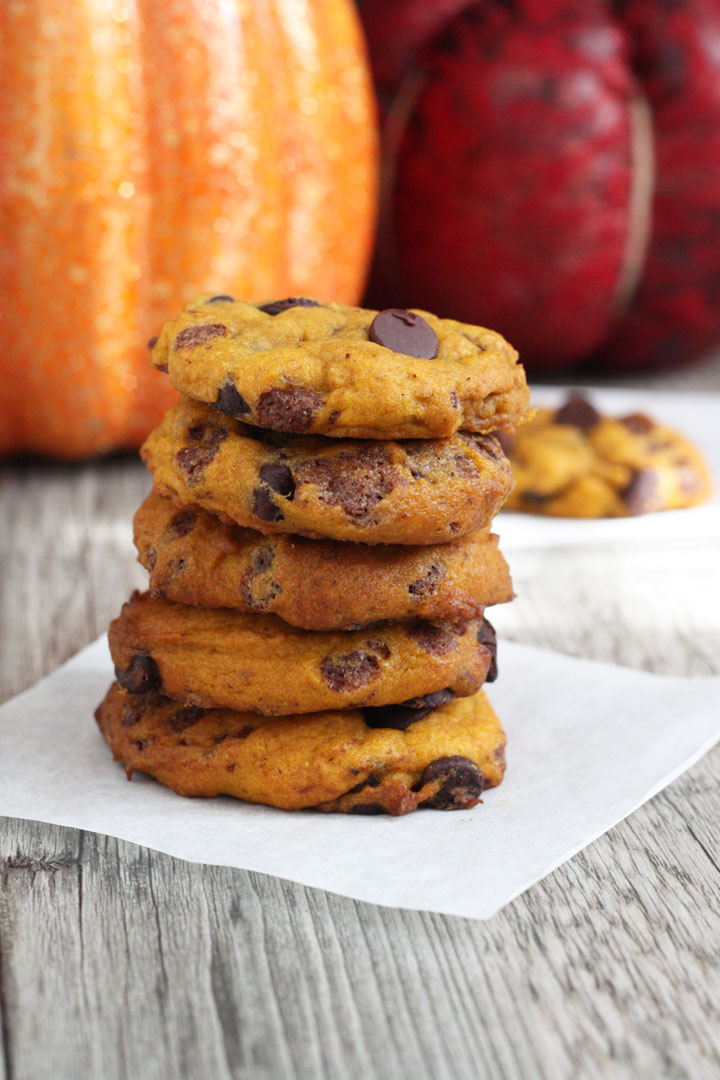 Stack of pumpkin chocolate chip cookies with pumpkins in the background.