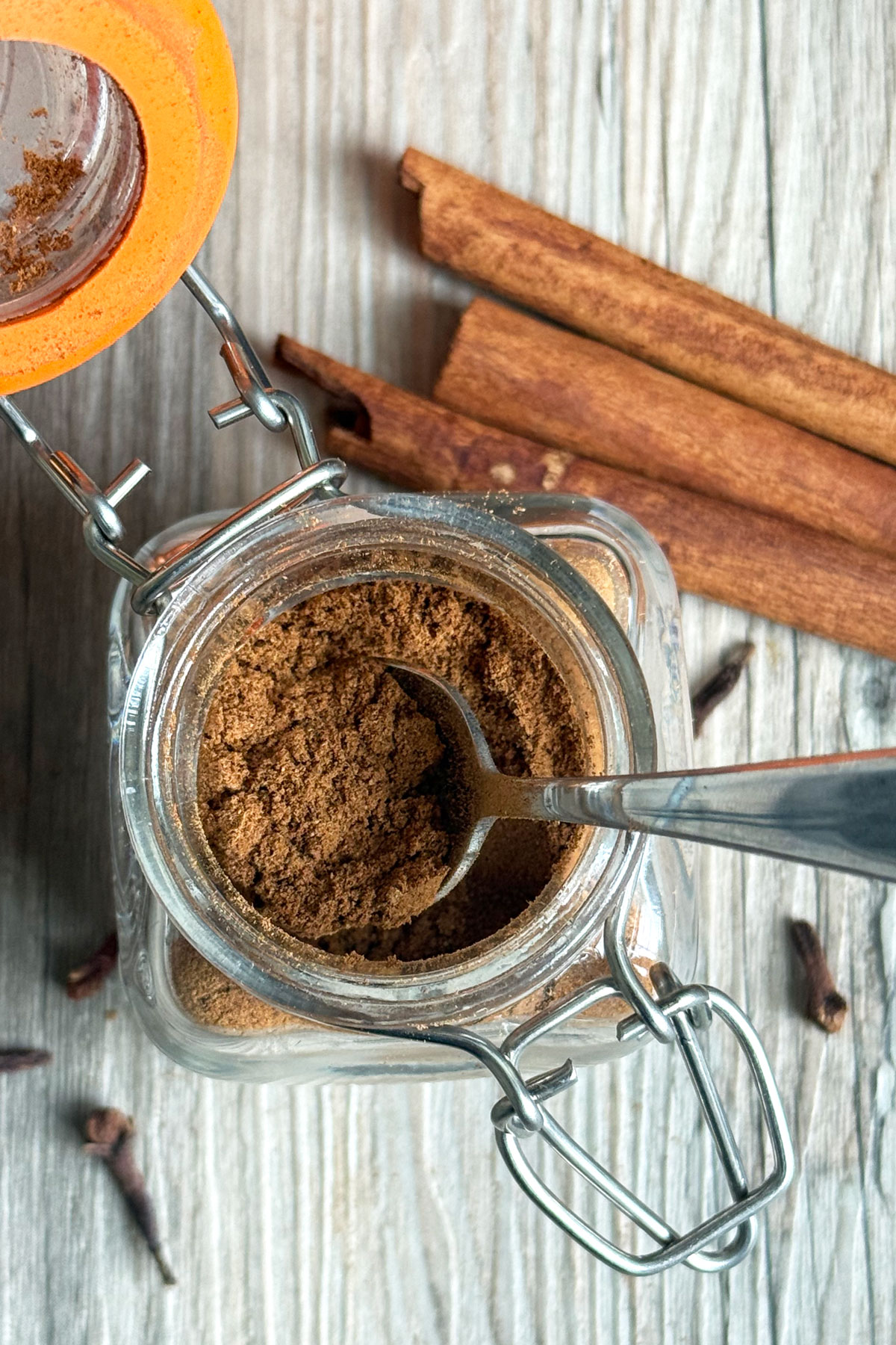 Top down view of open pumpkin pie spice jar with spoon.