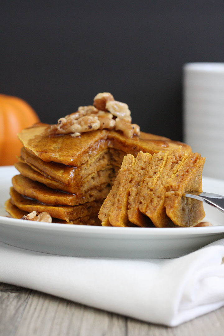 Whole grain pumpkin pancakes stack with pieces cut out onto a fork.