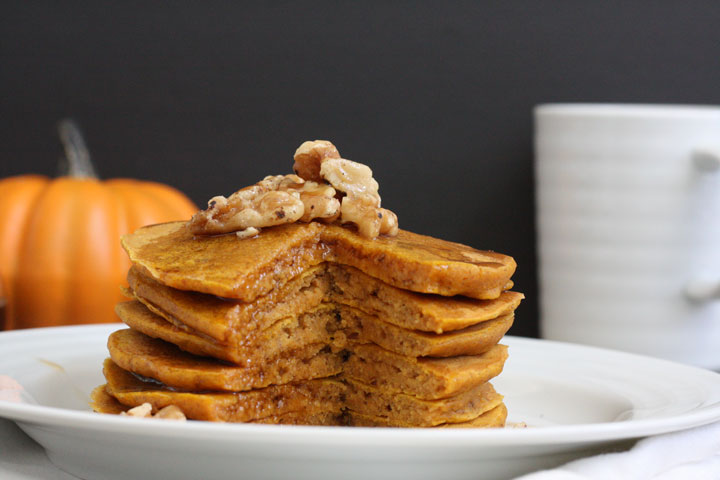Stack of whole grain pumpkin pancakes with piece cut out.