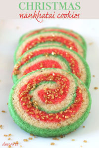 A row of Christmas Nankhatai Cookies with golden sugar crystals sprinkled around on a white background.