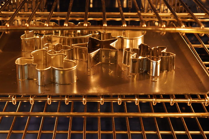 Cookie cutters drying in the oven on a cookie sheet.