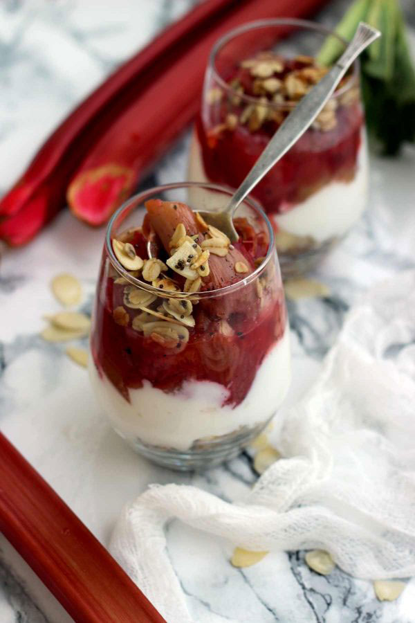 Cheesecake in a glass cup with roasted granola rhubarb topping.