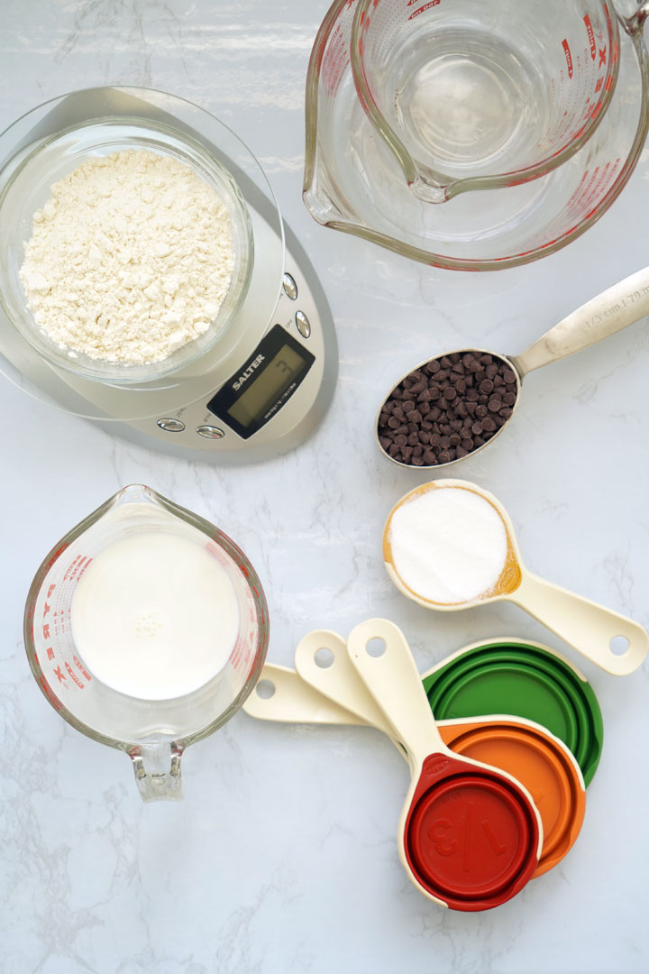 Top view of a digital food scale, various liquid measuring cups and dry measuring cups.