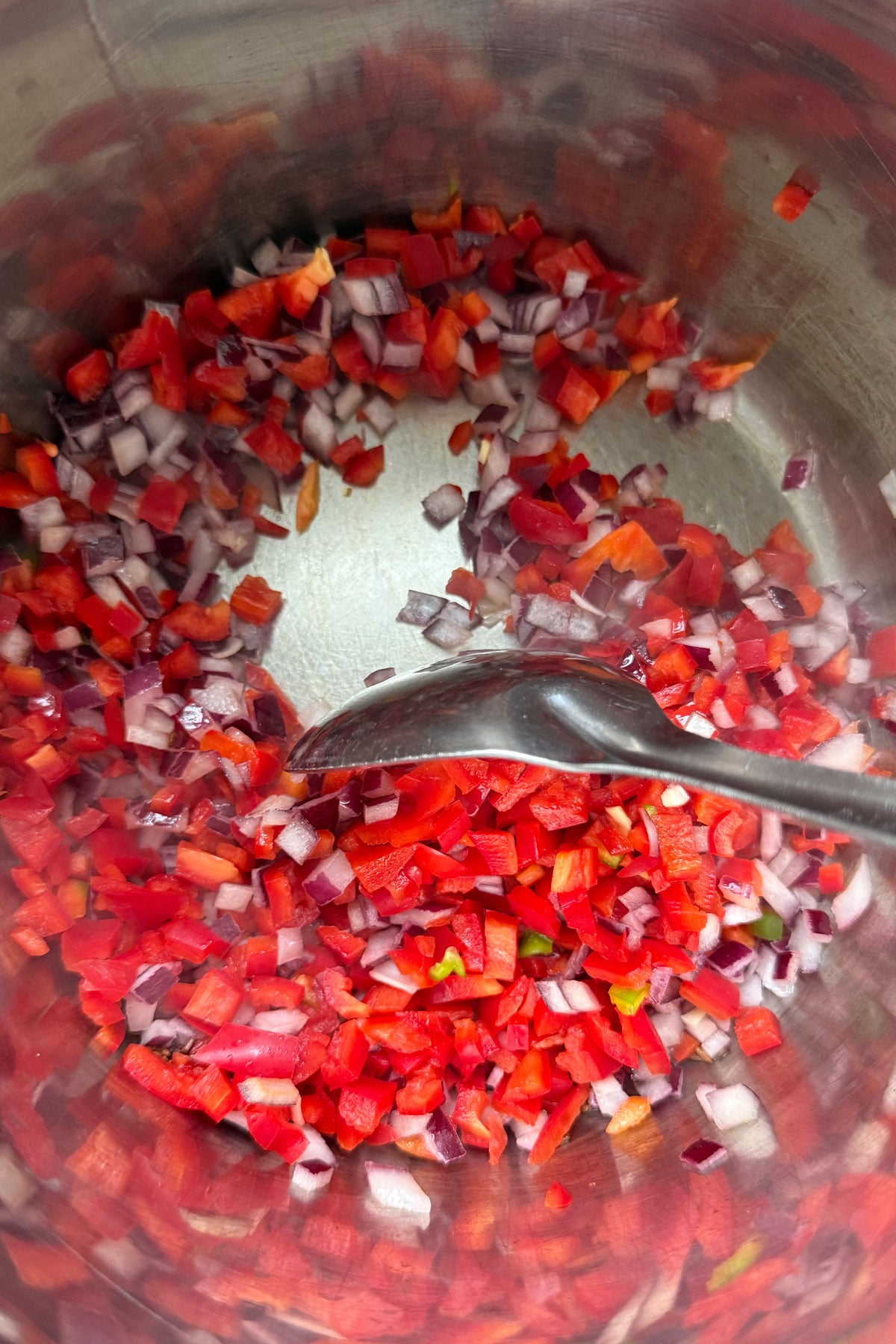 Onions and bell pepper being sauteed with tempering spices in Instant Pot.